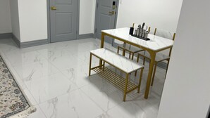 A dining area with a marble table and bench, a rug, and two grey doors.