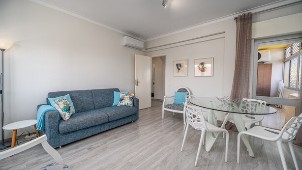 A modern living room with a grey sofa, white chairs, a glass table, and a white floor. - Holiday Home 'Beach Apartment  On The Beach' with Shared Terrace, Wi-Fi and Air Conditioning (Portimão)