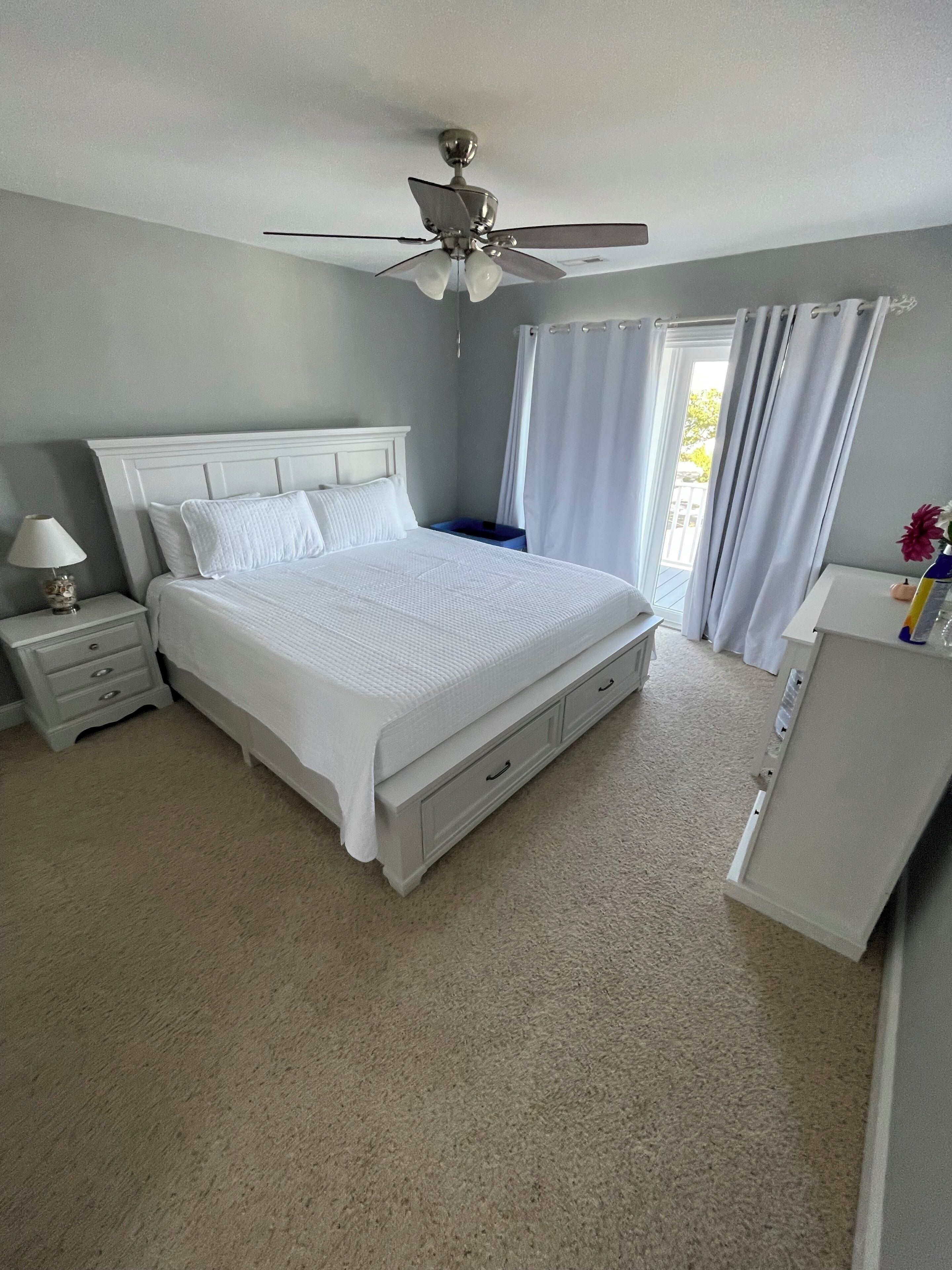 A bedroom with a bed, nightstand, dresser, and ceiling fan.