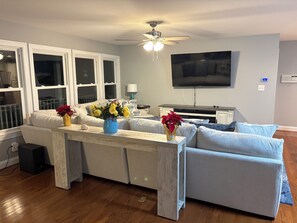 A living room with a sofa, a coffee table, a TV, and a ceiling fan.