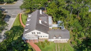 Vue aérienne d’une maison à deux étages, dotée d’un grand jardin à l’avant, d’un garage et d’une allée.