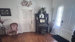 Une pièce spacieuse dotée d’un parquet, d’un magnifique piano à queue, d’un fauteuil moelleux et d’une décoration murale.