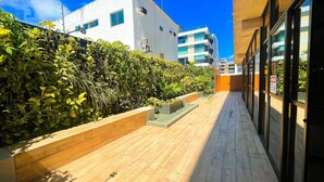 A narrow pathway flanked by lush greenery and modern buildings. - Flat FM20 Cabo Branco Deluxe - By Almare (João Pessoa)