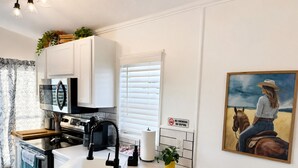 A modern kitchen with white cabinetry, a stainless steel range, and a black faucet. - Peaceful Pondside Stay (Archie)