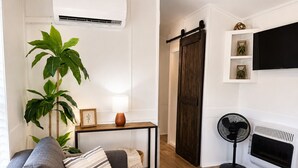 A living room with a sofa, a table, a fan, a fireplace, and a sliding door. - Peaceful Pondside Stay (Archie)