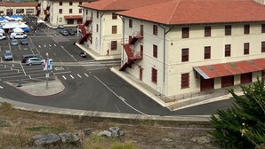 A parking lot with several buildings, including a multi-story structure with red-tiled roofs and a staircase. - Da Hotel OCt (North Vancouver)