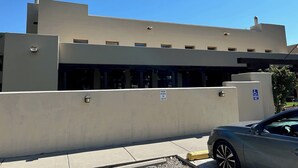 A modern building with a flat roof, large windows, and a parking sign indicating reserved parking for check-in. - Da Hotel OCt (North Vancouver)