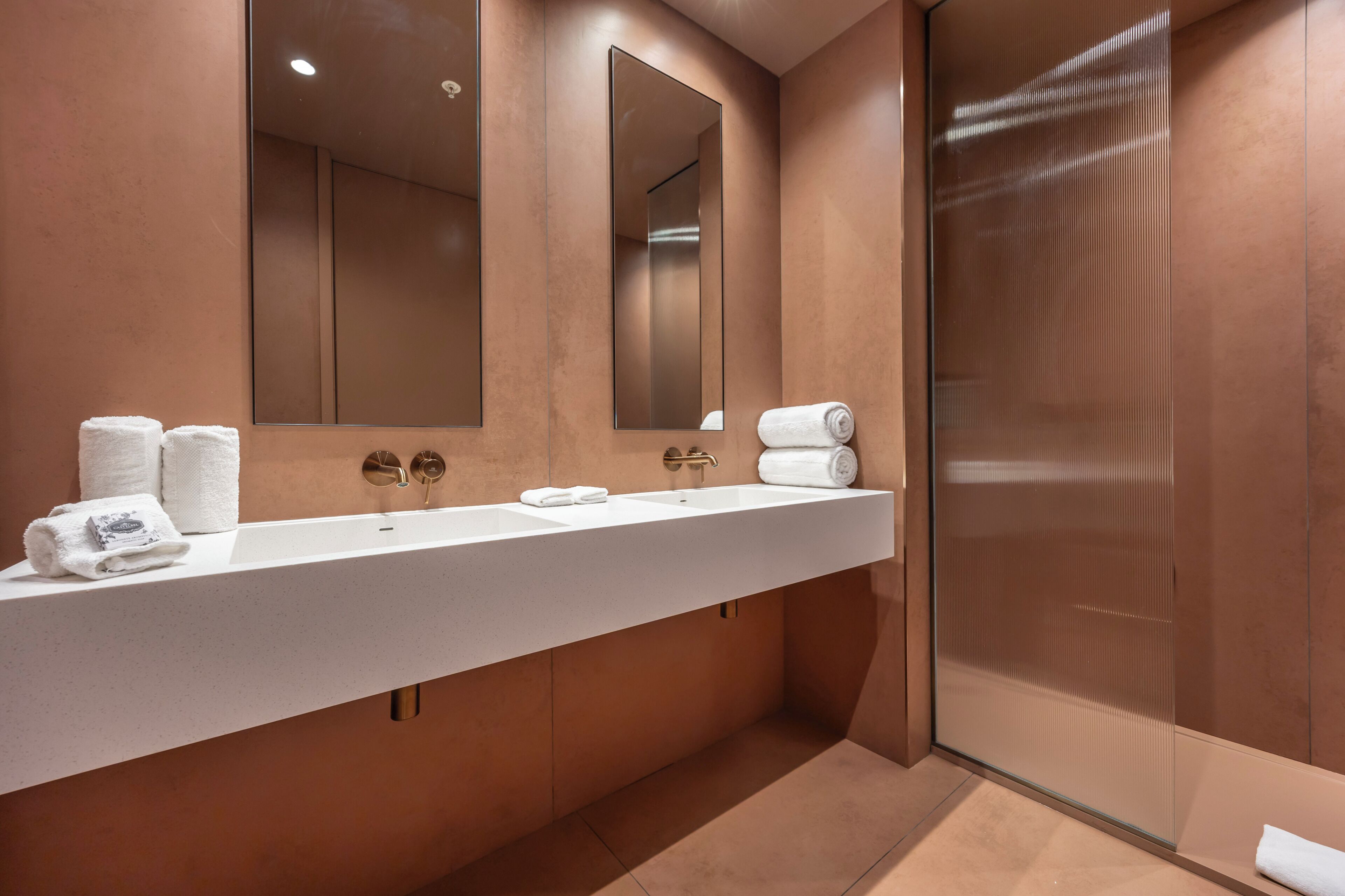 A modern bathroom with a large mirror, a sink, and a glass shower enclosure.