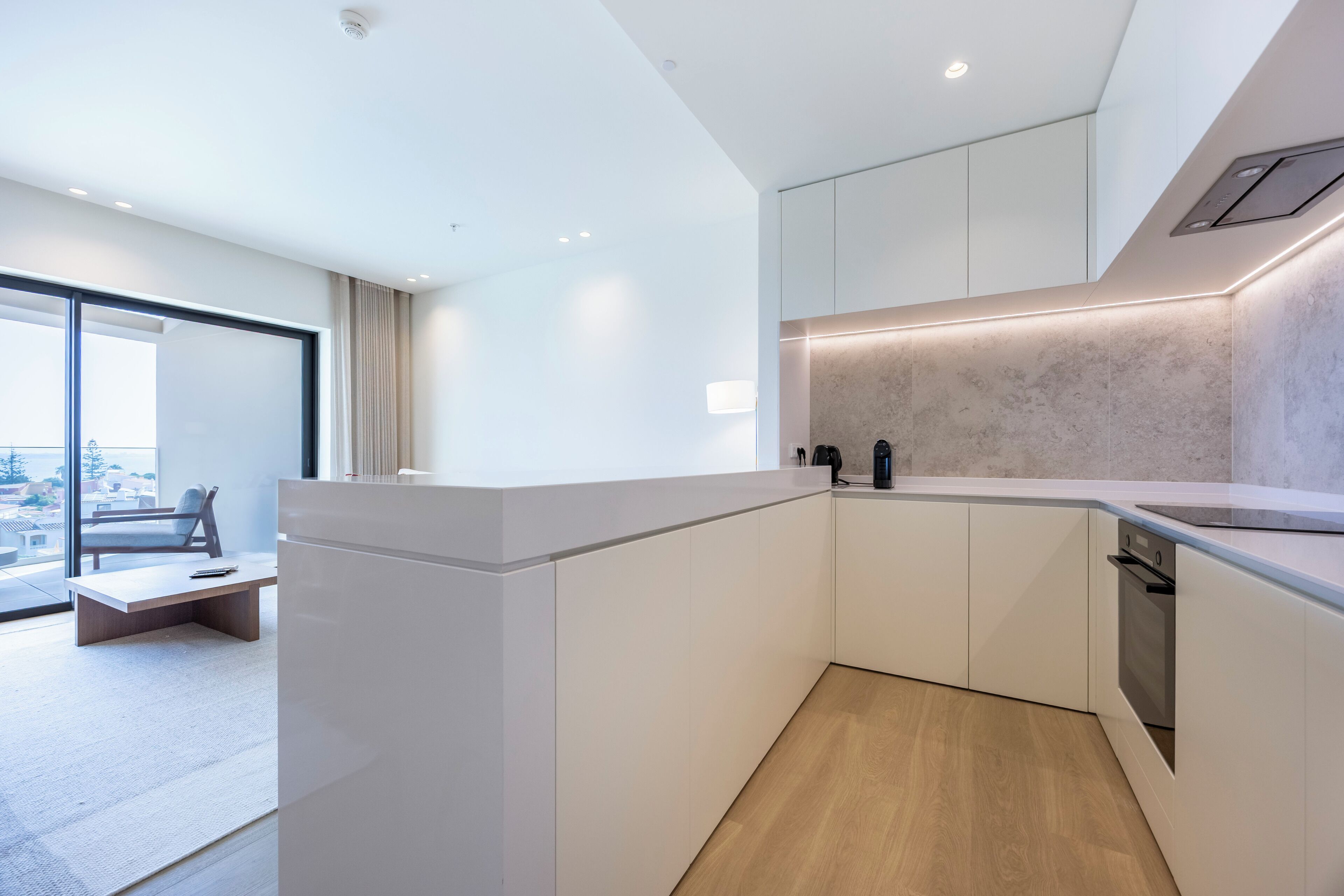 Una cocina moderna con armarios blancos, horno empotrado y un amplio ventanal con vista a la ciudad.