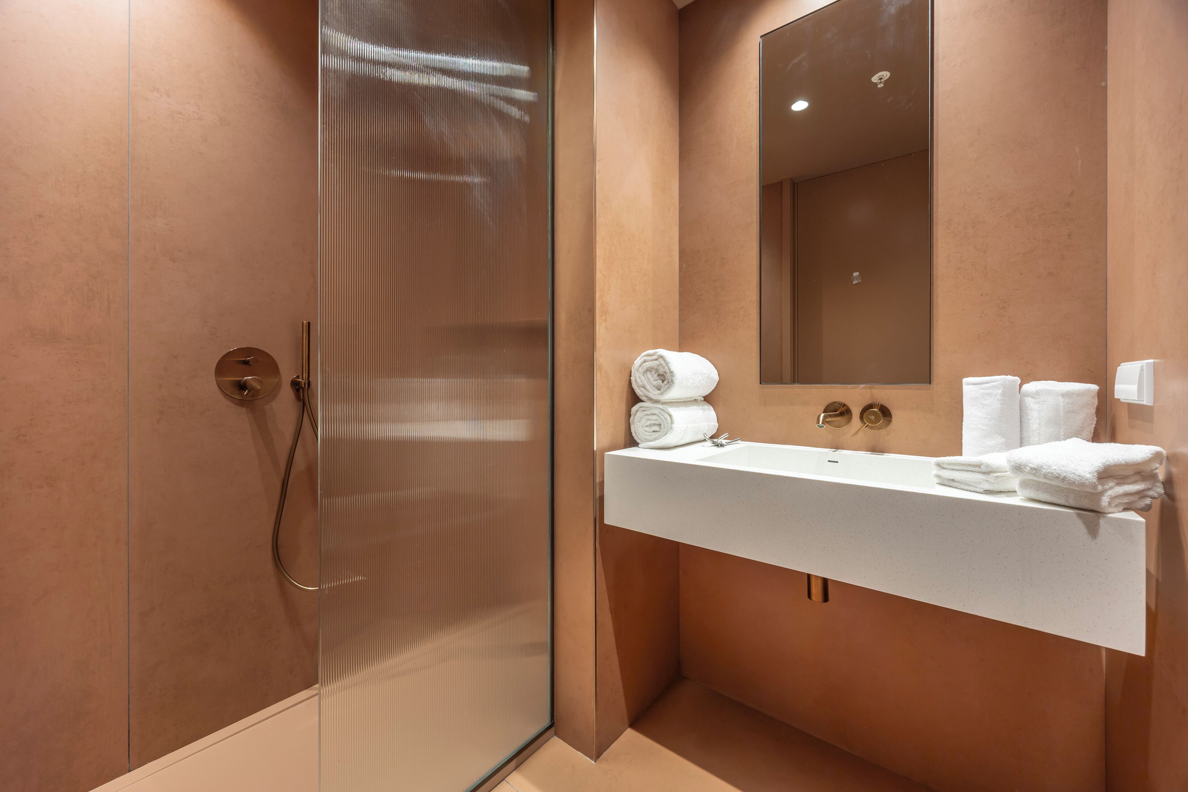 A modern bathroom with a glass shower enclosure, a white sink, and a large mirror.
