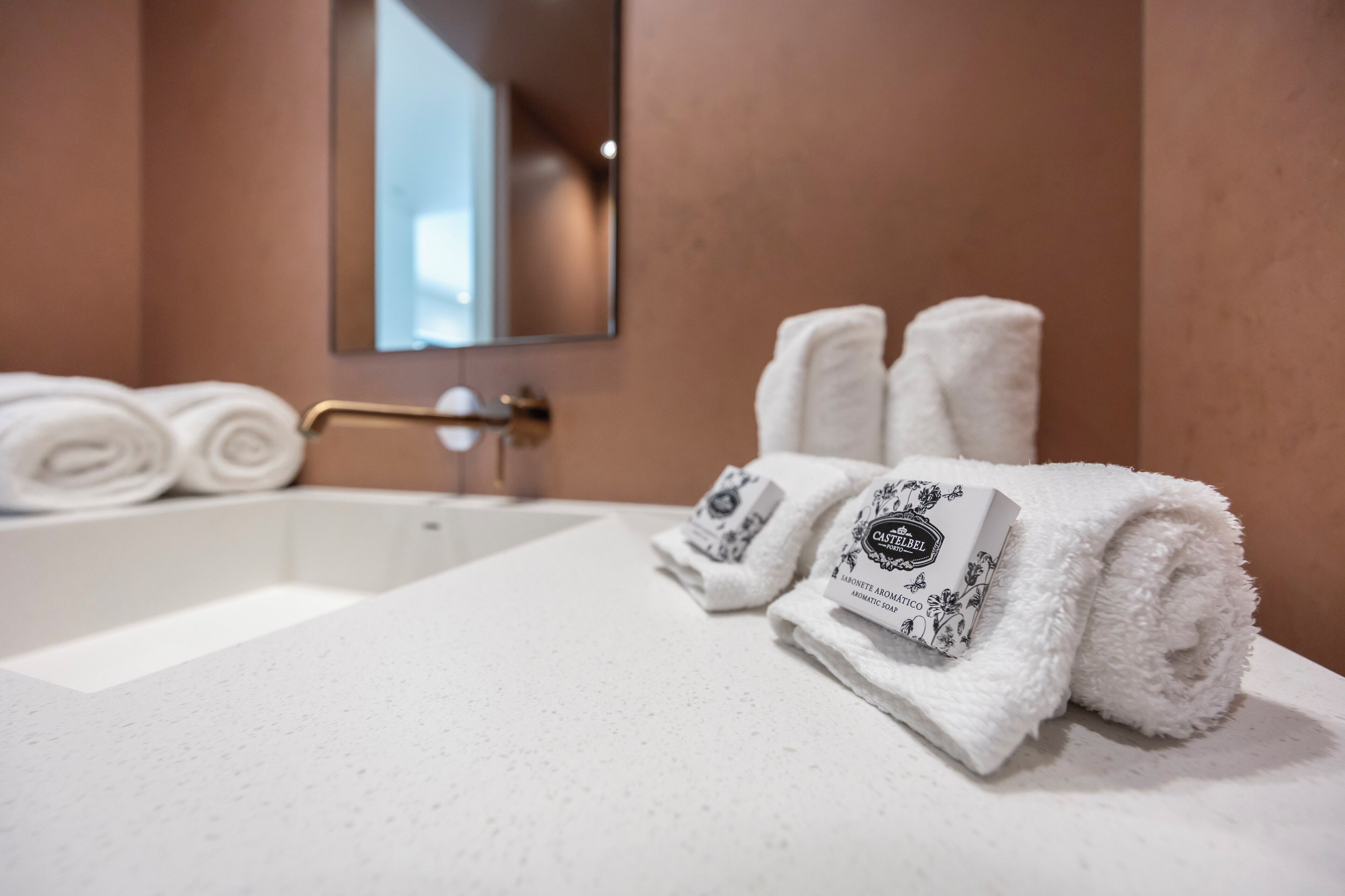 A bathroom with a white sink, a towel rack with folded towels, and a mirror above the sink.