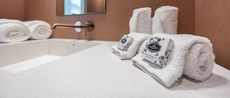 A bathroom with a white sink, a towel rack with folded towels, and a mirror above the sink.