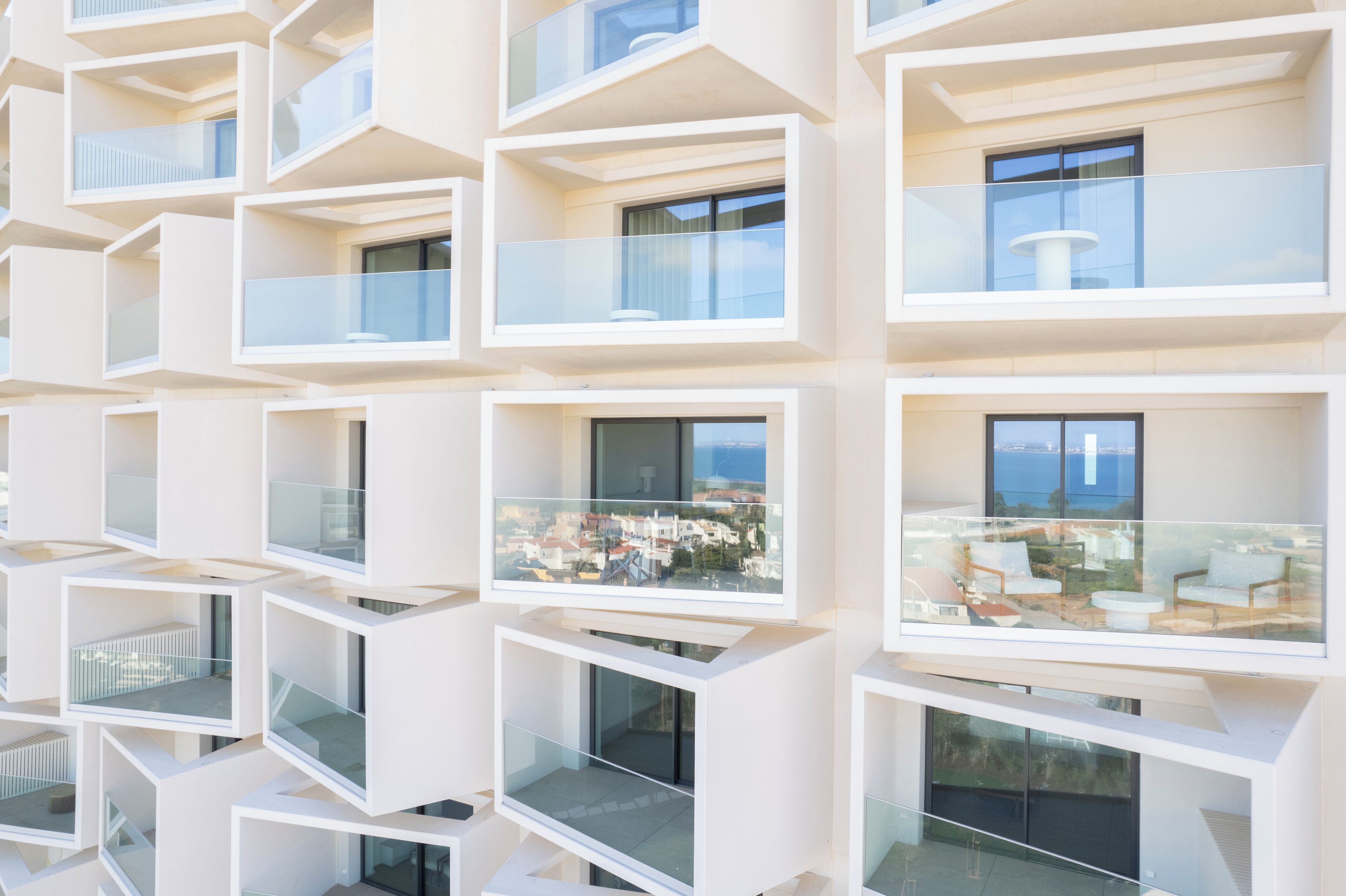 A modern building with multiple balconies, each with glass railings and a view of the cityscape.