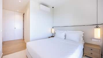 A bedroom with a large bed, bedside tables, a wardrobe, and an air conditioning unit.