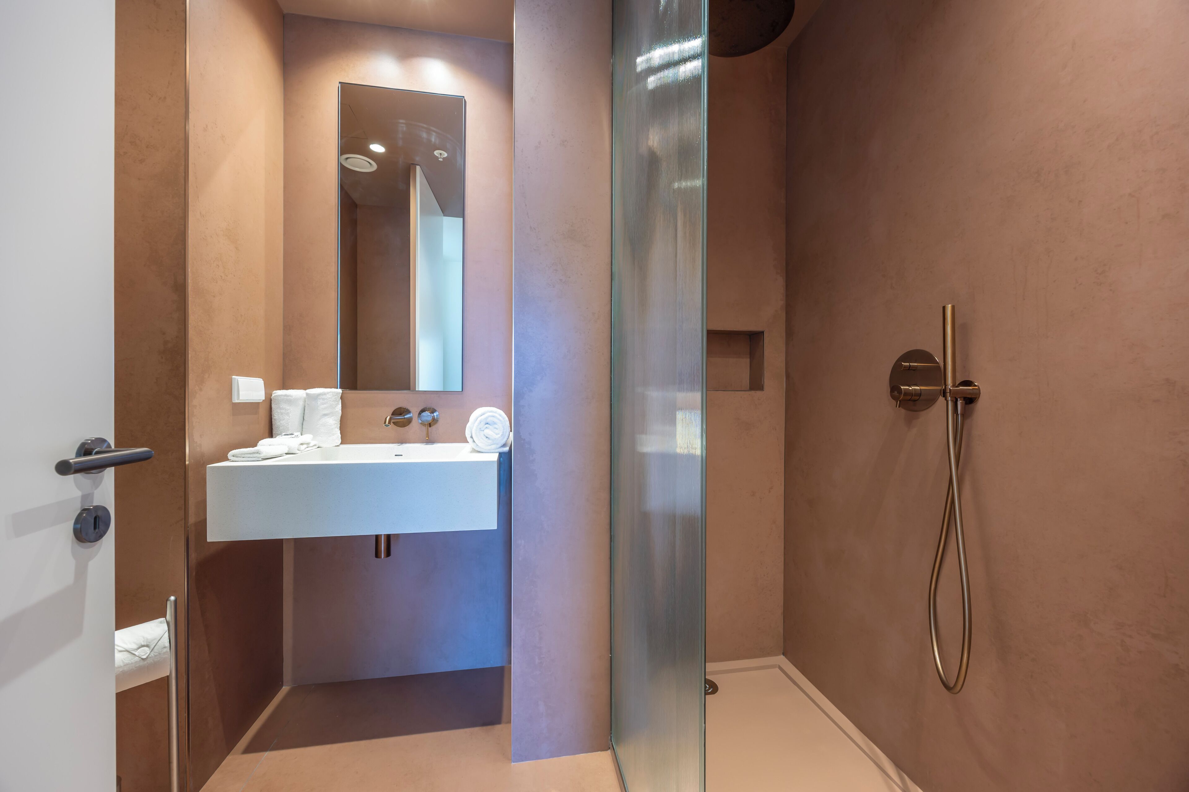 Une salle de bain moderne avec une douche à parois de verre, un lavabo blanc et un grand miroir.