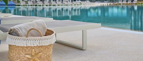 A poolside area with lounge chairs and a woven basket with a starfish design.