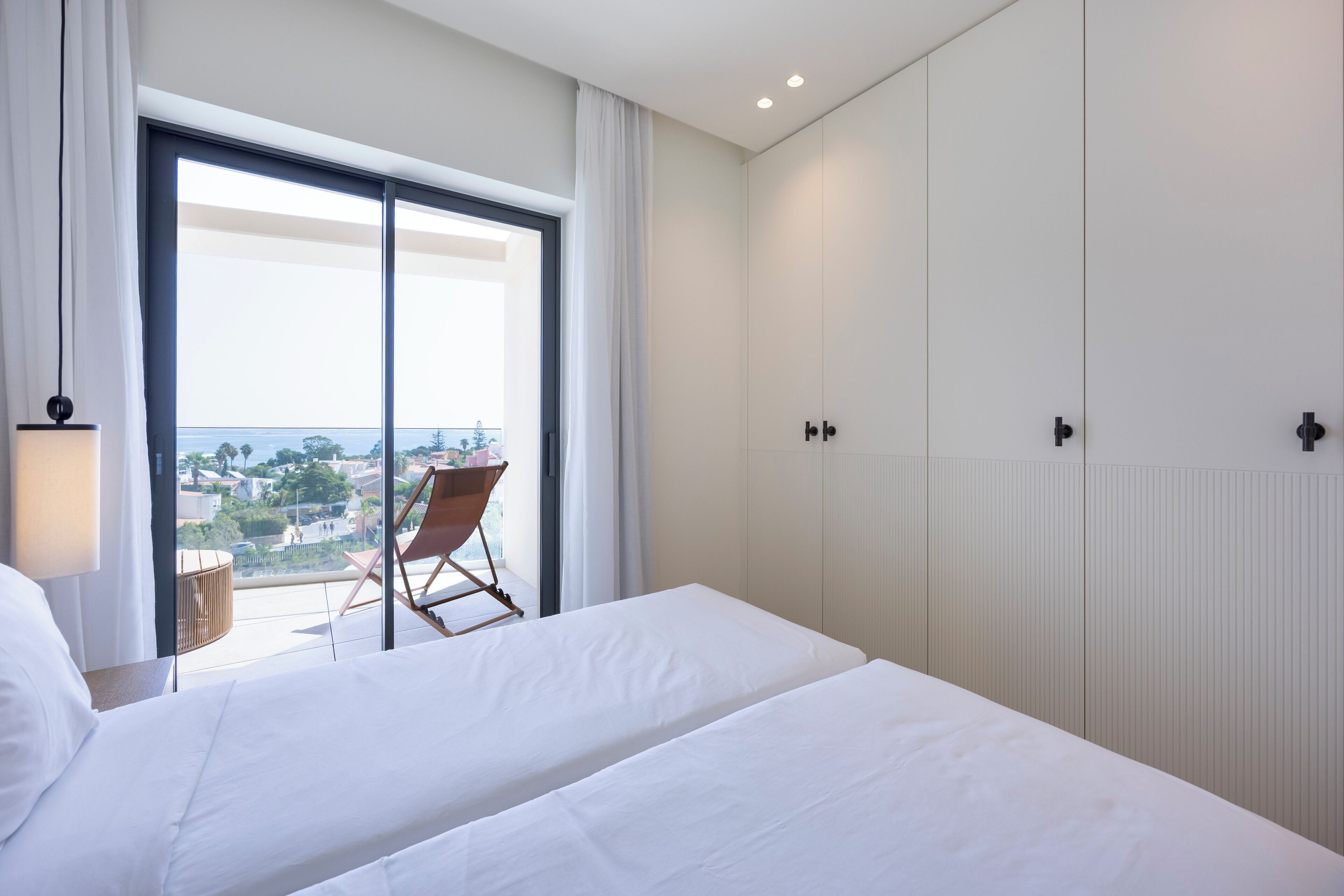 Une chambre d’hôtel avec un grand lit, un fauteuil près de la fenêtre et une vue sur la ville.
