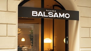 A hotel entrance with a sign reading "PALAZZO BALSAMO" and a modern interior visible through the glass doors. - Palazzo Balsamo  (Palermo)