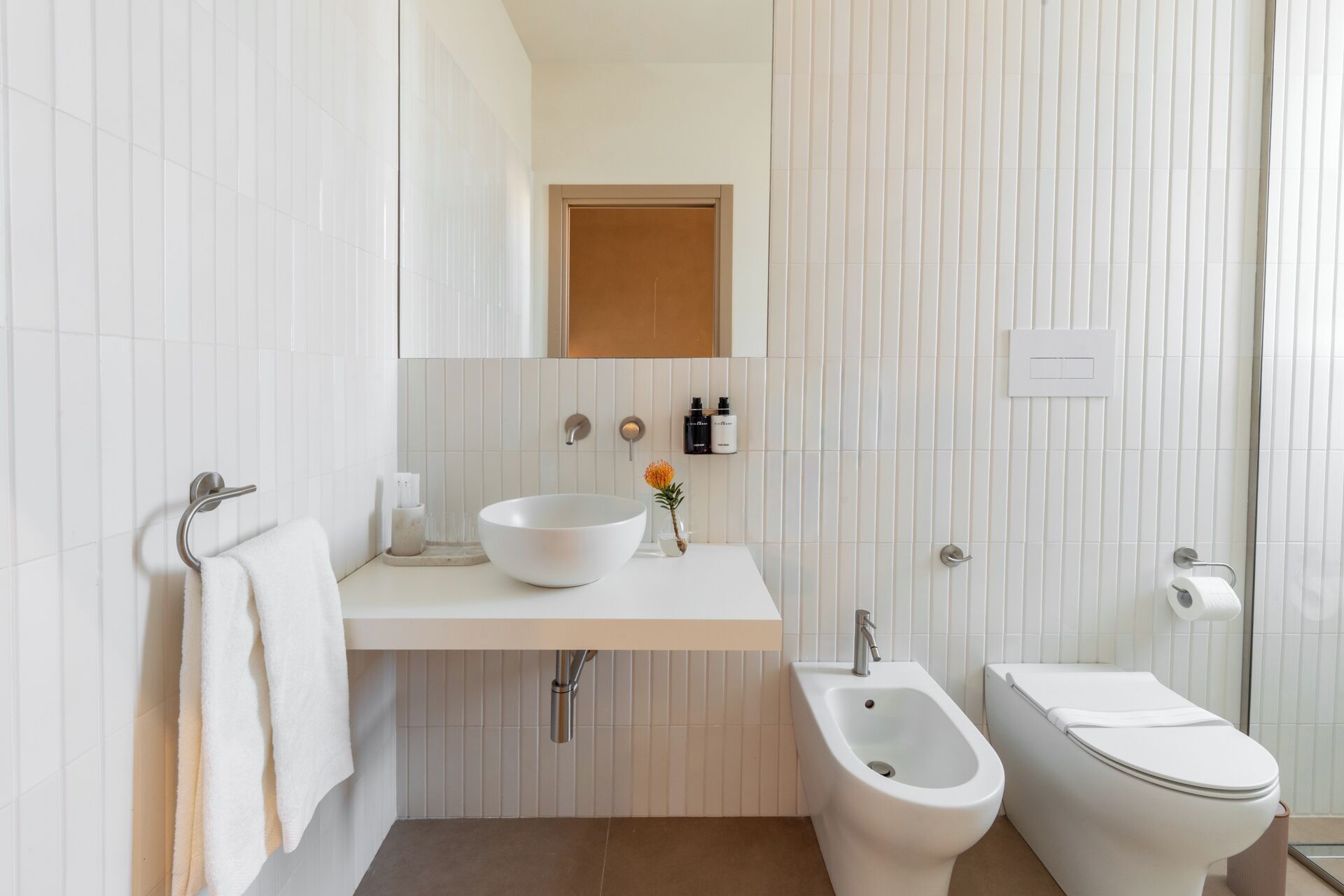 A modern bathroom with a white sink, a bidet, and a toilet.