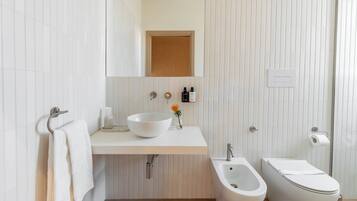 A modern bathroom with a white sink, a bidet, and a toilet.