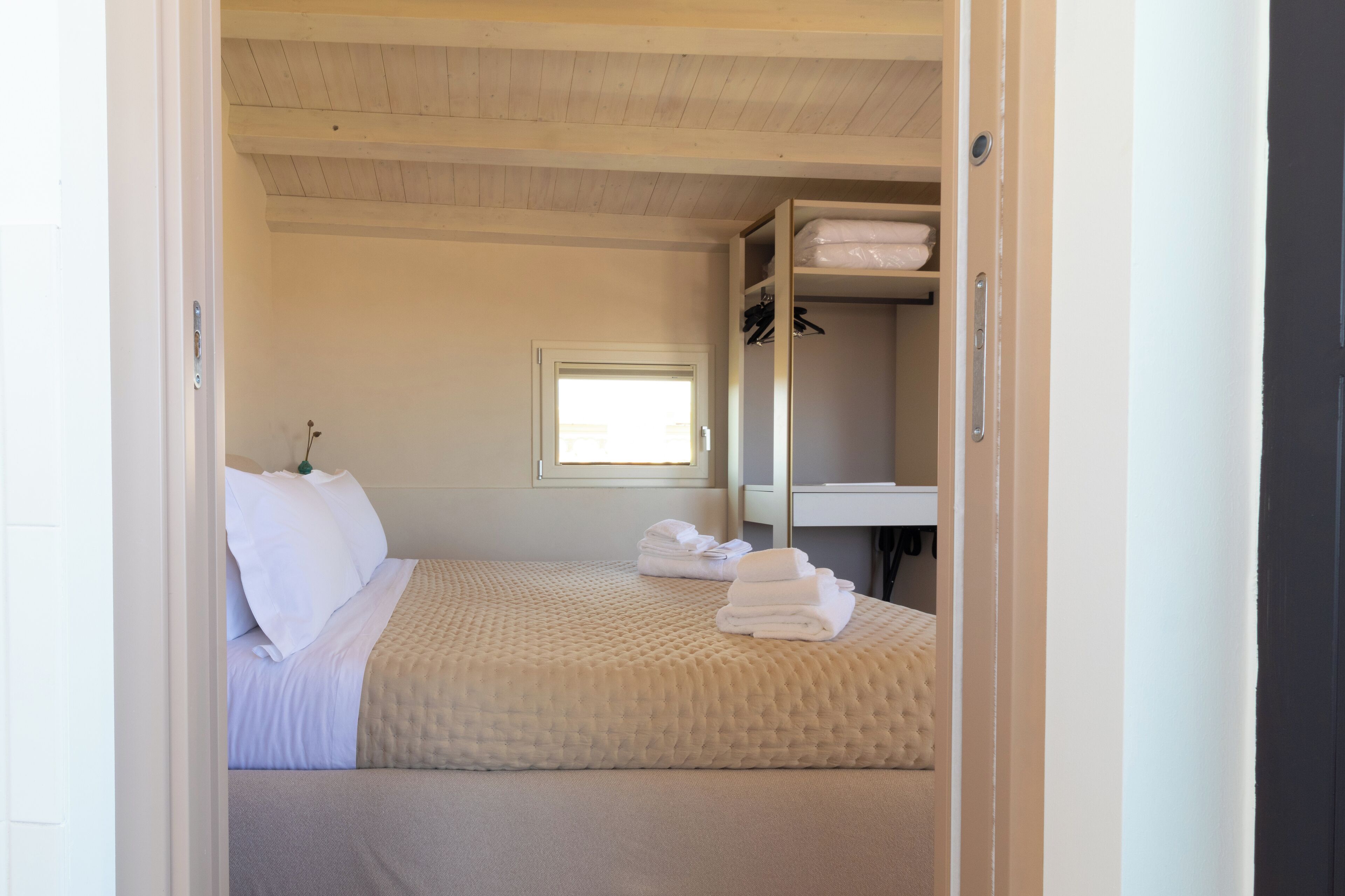 Un dormitorio con cama, ventana, mesita de noche y armario.