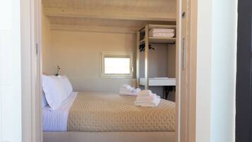 Un dormitorio con cama, ventana, mesita de noche y armario.