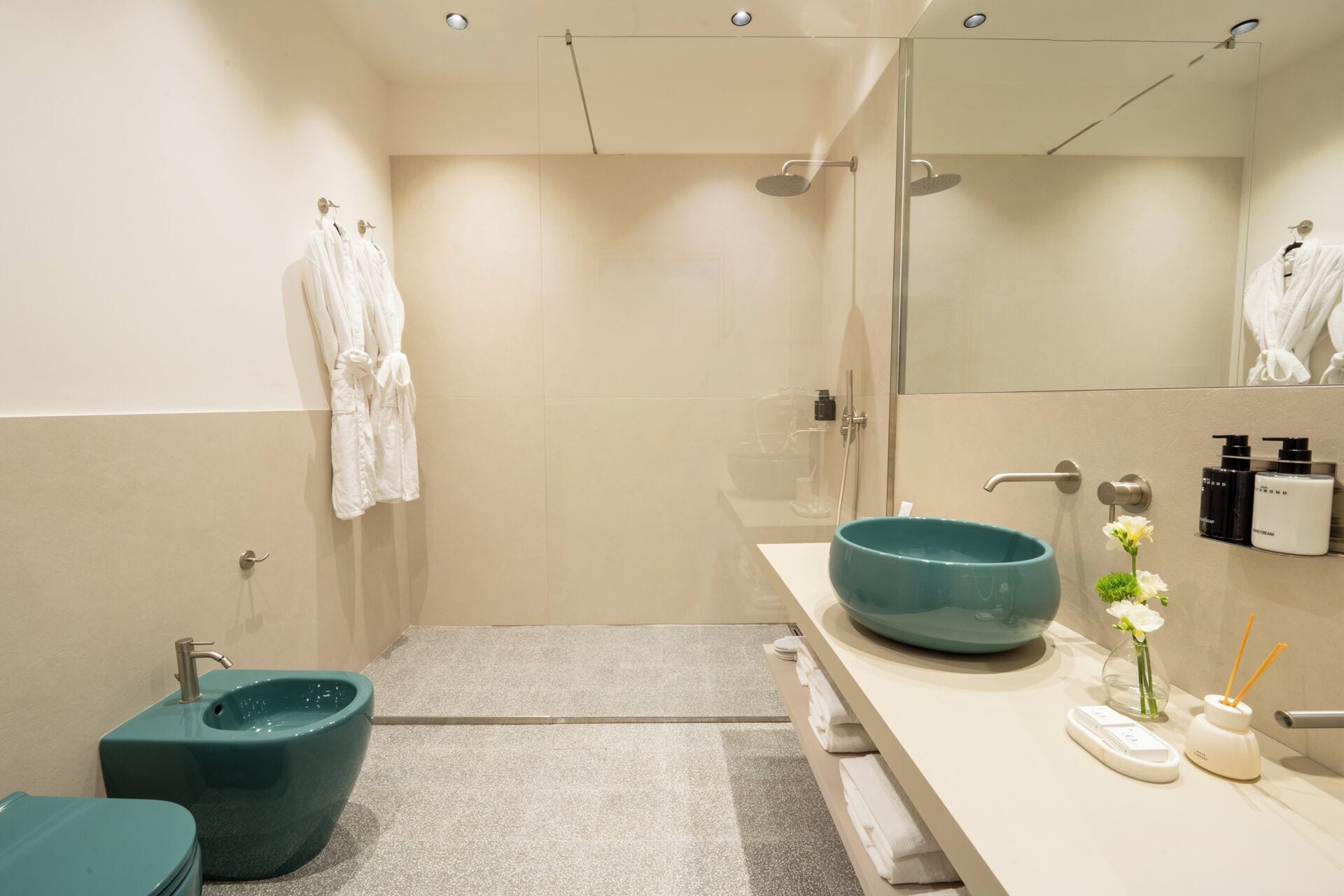 A modern bathroom with a large mirror, a blue sink, and a shower area.