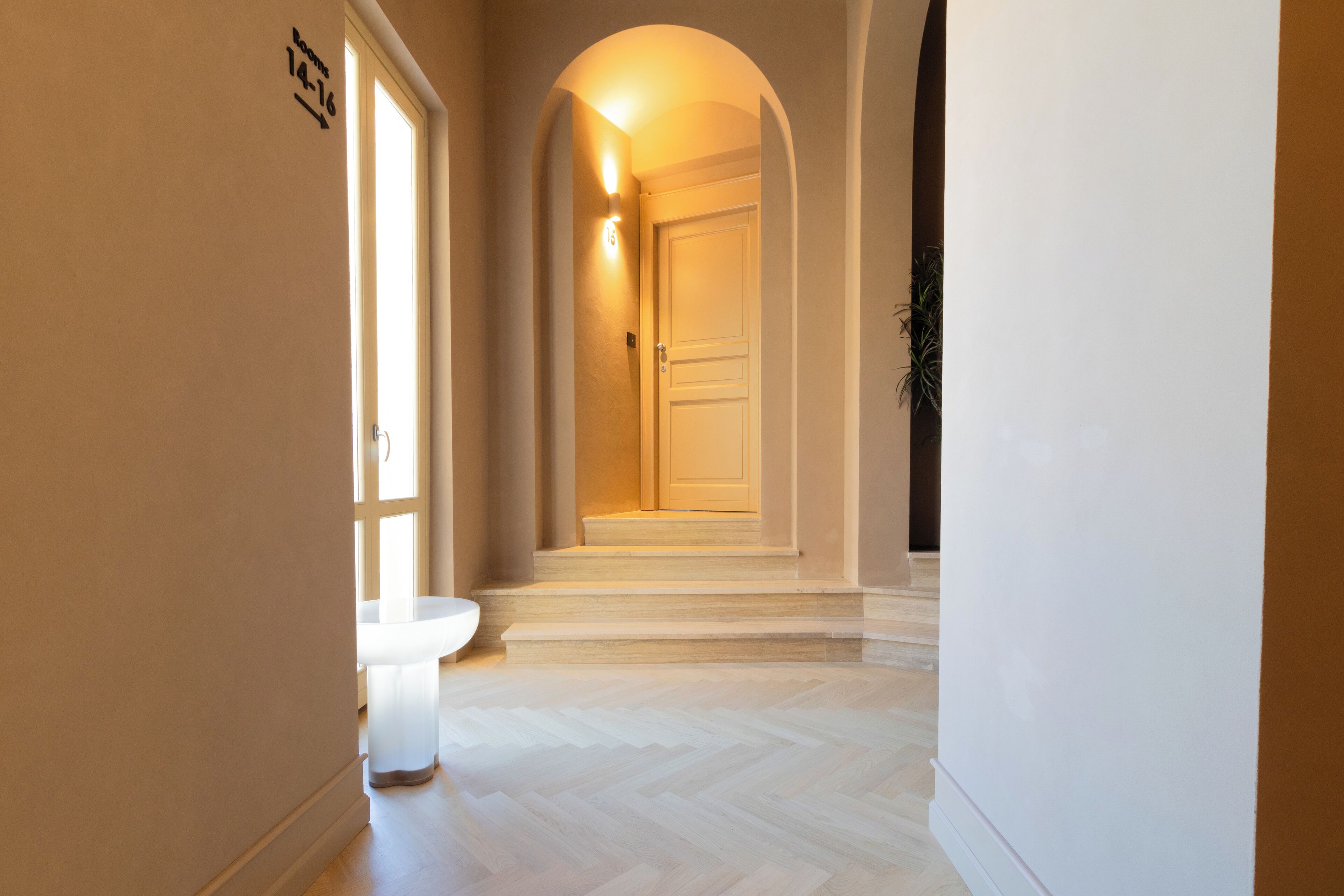 A hallway with a toilet, a door, and a staircase leading to another room.