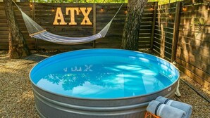 A round swimming pool with a hammock and towels nearby, surrounded by a wooden fence and trees. - 5BR Oasis - Pool + Hot Tub + Games - Walk to Fun! (Austin)