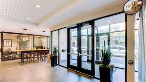 Rebedor d'hotel amb taulell de recepció, zona de seients i grans portes de vidre que donen a l'exterior.