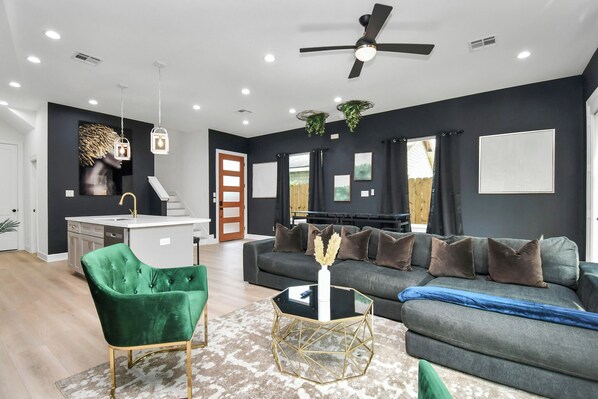 A modern living room with a grey sofa, green armchair, and a black coffee table.