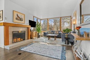 A spacious living room with a fireplace, a large window, a sofa set, and a coffee table.
