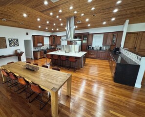 Una cocina amplia con armarios de madera, una isla central y un comedor con mesa y sillas de madera.