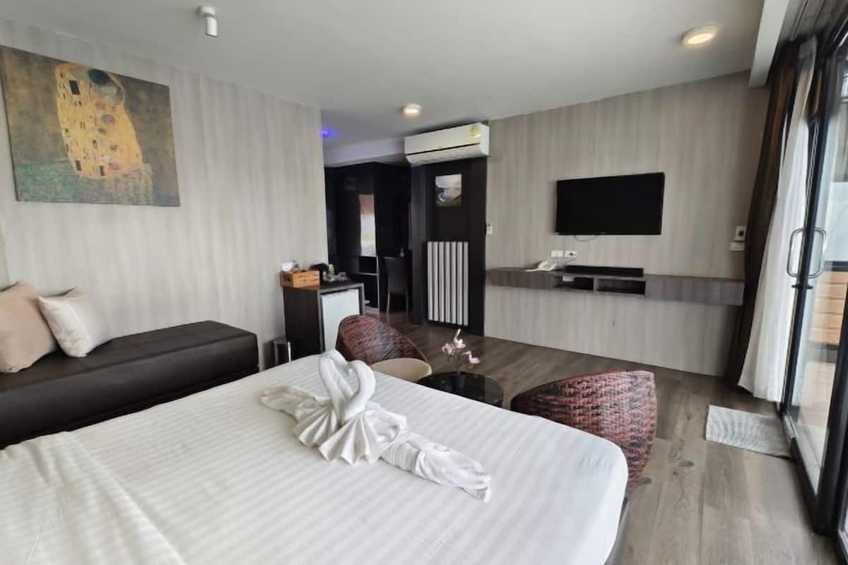 A hotel room with a large bed, a desk, a flat-screen TV, and a painting on the wall.