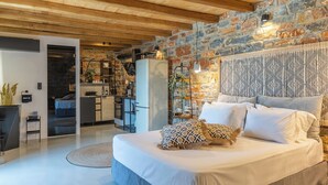 Ein modernes Schlafzimmer mit einem großen Bett, einer Steinsäule und einer Holzbalkendecke.