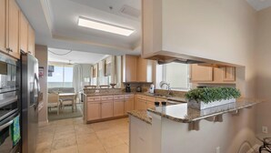 A modern kitchen with granite countertops, stainless steel appliances, and wooden cabinets. - Indigo West 1404 (Pensacola)