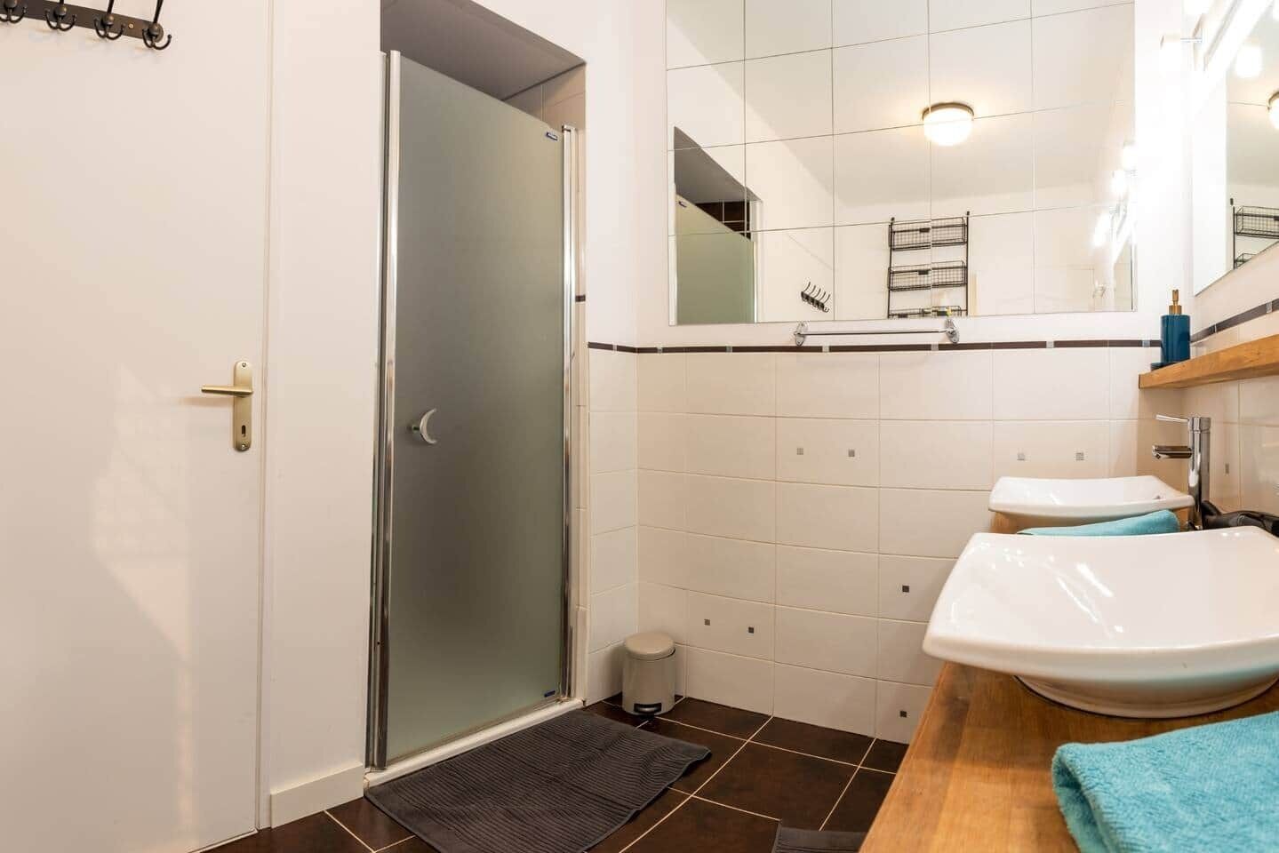 A bathroom with a glass shower door, a sink, and a mirror.