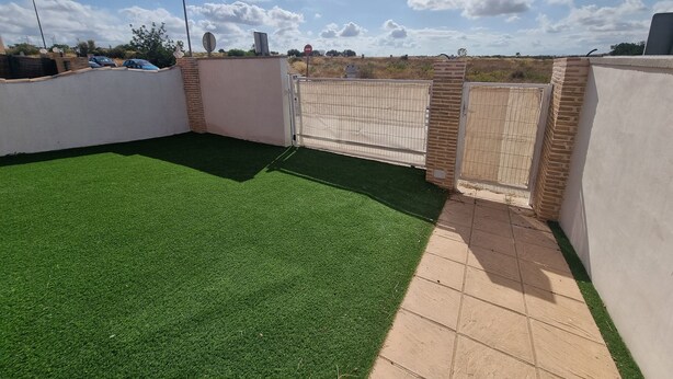 A rooftop with artificial green turf, a gated entrance, and a clear sky.