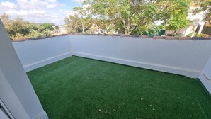 A small, enclosed patio area with artificial green turf and white walls.