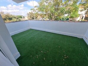 A small, enclosed patio area with artificial green turf and white walls. - Hidden Gem between Mountains & Sea (La Tercia)