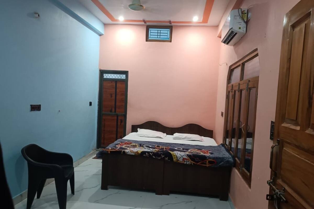 Une petite chambre avec un lit, une chaise, une fenêtre et une porte.