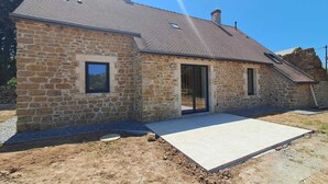 A stone building with a sloped roof, a door, and a small window. - Maison neuve 2 chambres au calme à Ceaulmont (Ceaulmont)
