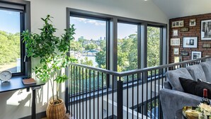 A modern living room with large windows, a balcony, and a city view. - Entire House Free Parking/Sleeps 26/MIT/Harvard/TD (Somerville)