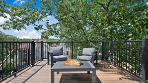 An outdoor deck with a wooden floor, two grey chairs, a table with a tray of drinks, and a black railing. - Entire House Free Parking/Sleeps 26/MIT/Harvard/TD (Somerville)