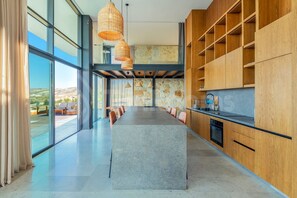 Une cuisine moderne dotée d’un îlot central, d’étagères en bois et d’un mur d’accent en pierre.