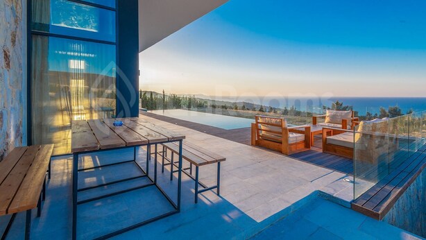 A modern outdoor terrace with a pool, wooden furniture, and a glass railing overlooking a scenic landscape.