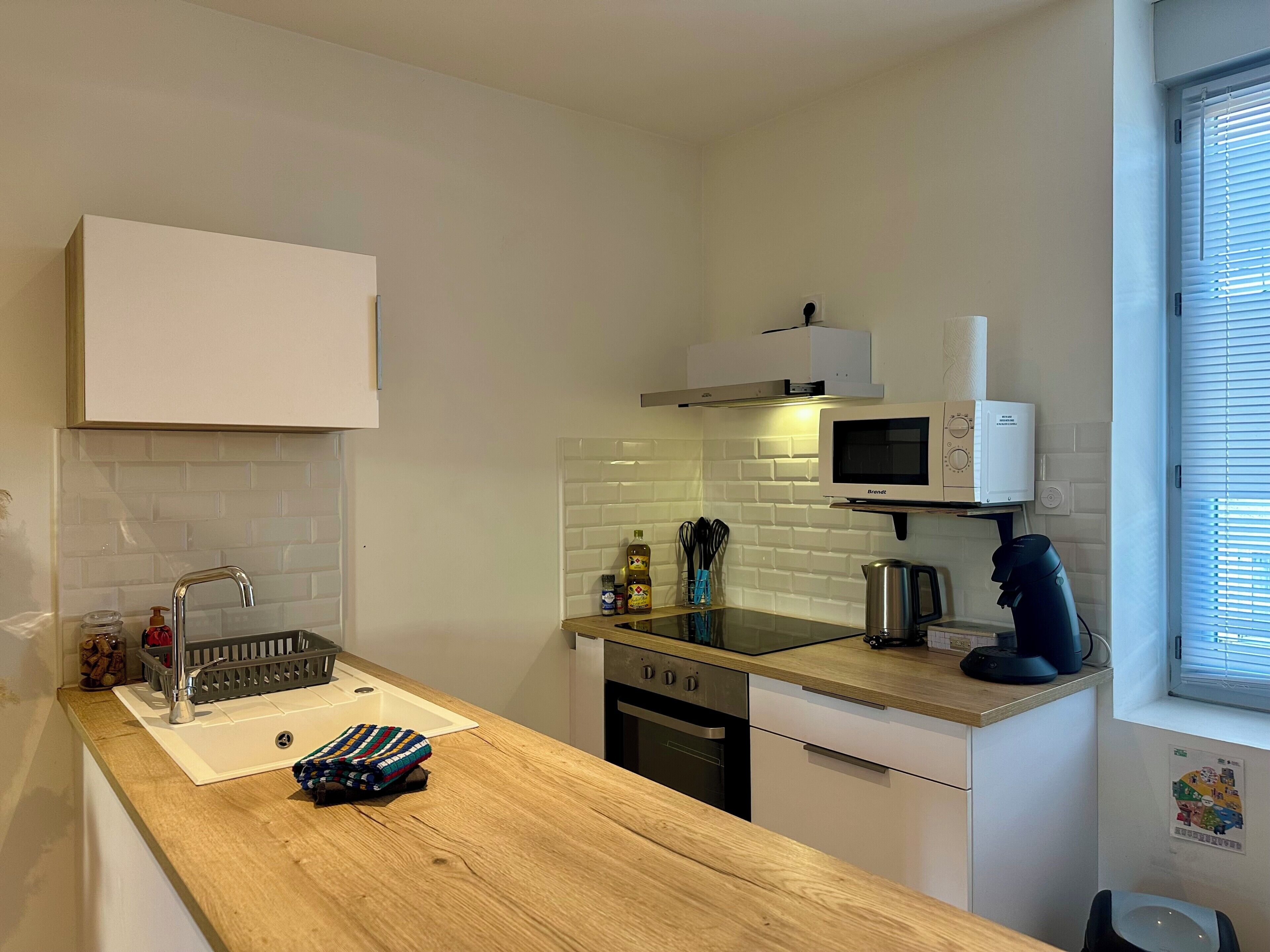 A compact kitchen with a wooden countertop, a built-in microwave, a kettle, and a coffee maker.