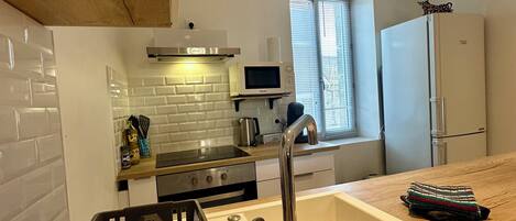 Una cocina moderna con azulejos tipo metro blancos, electrodomésticos de acero inoxidable y un ventanal con persianas.