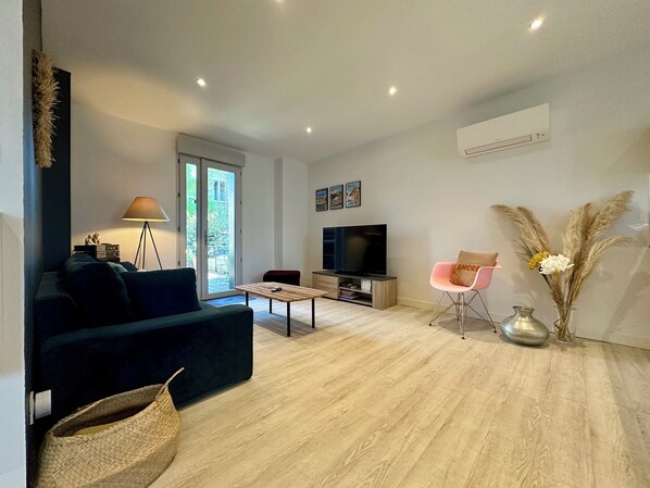 A modern living room with a sofa, coffee table, TV, and decorative items.