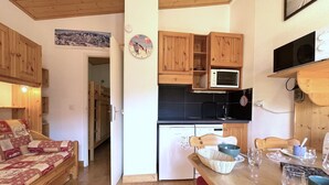Ett mysigt kök med träskåp, en mikrovågsugn och en matplats med ett bord och stolar.